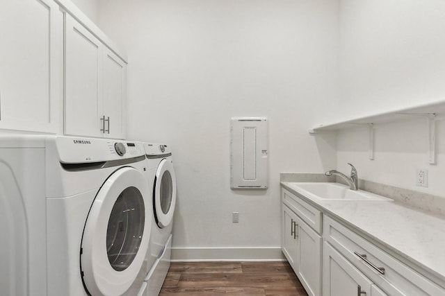 clothes washing area featuring cabinets, washing machine and dryer, dark wood-type flooring, and sink