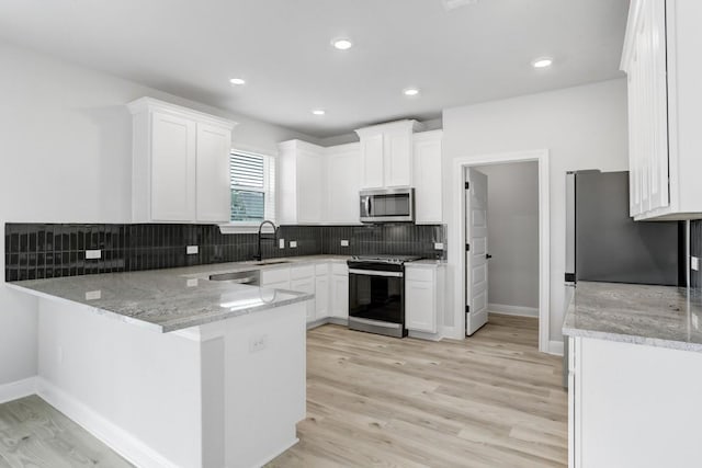 kitchen with white cabinetry, sink, stainless steel appliances, kitchen peninsula, and light wood-type flooring