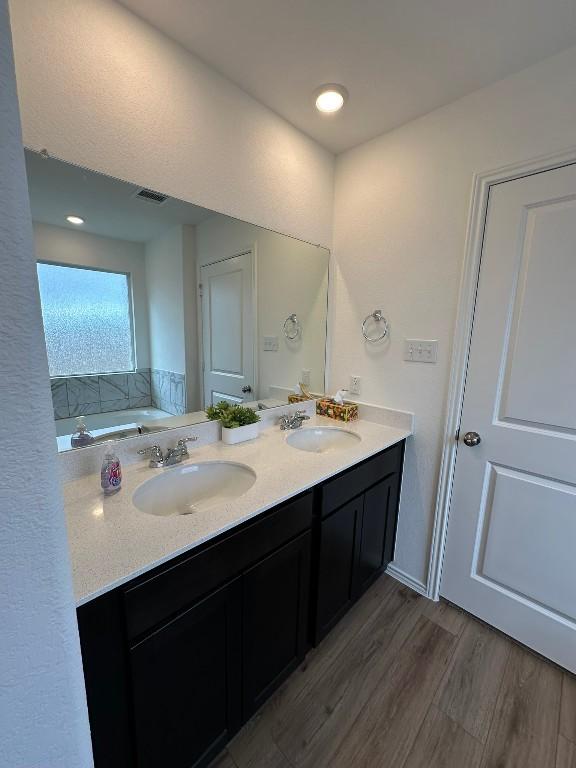 bathroom featuring hardwood / wood-style floors, vanity, and a tub to relax in