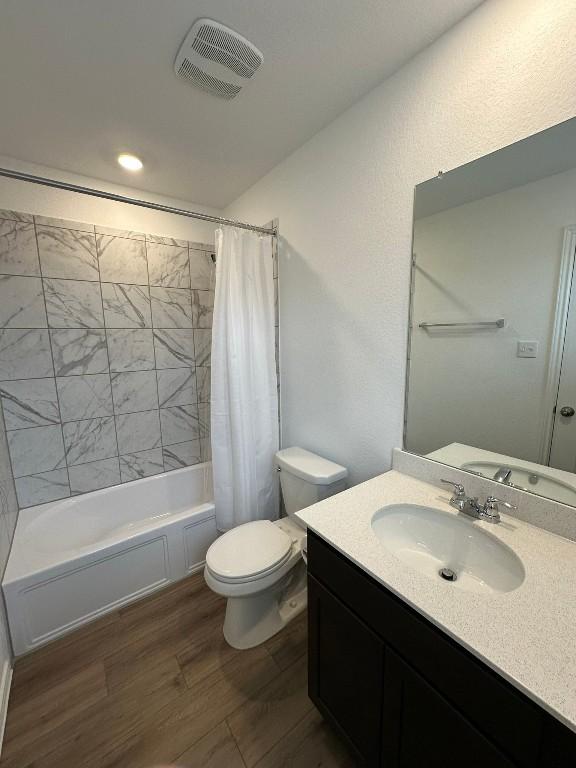 full bathroom featuring shower / bath combo, vanity, hardwood / wood-style flooring, and toilet