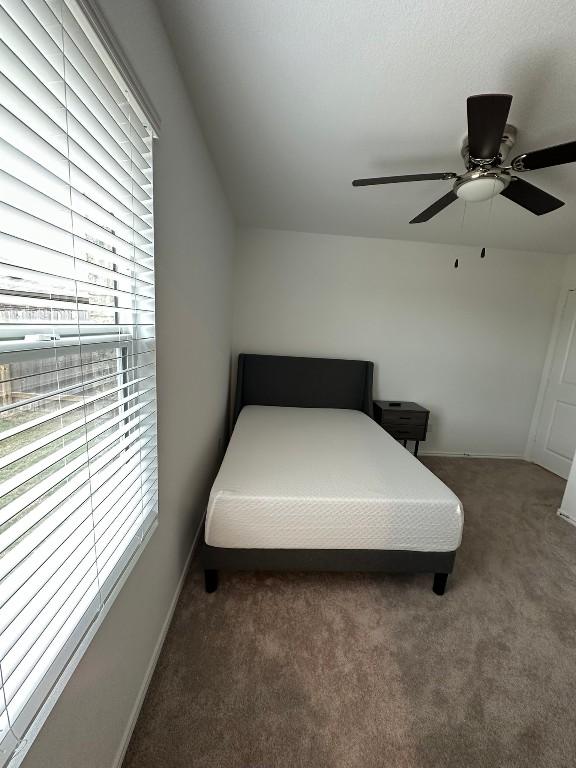 bedroom featuring multiple windows, ceiling fan, and dark colored carpet