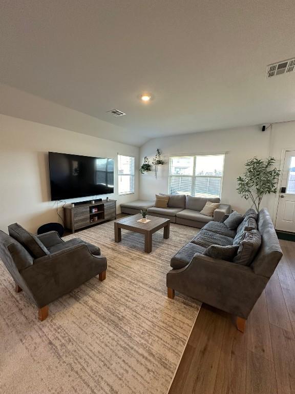 living room featuring wood-type flooring, plenty of natural light, and lofted ceiling