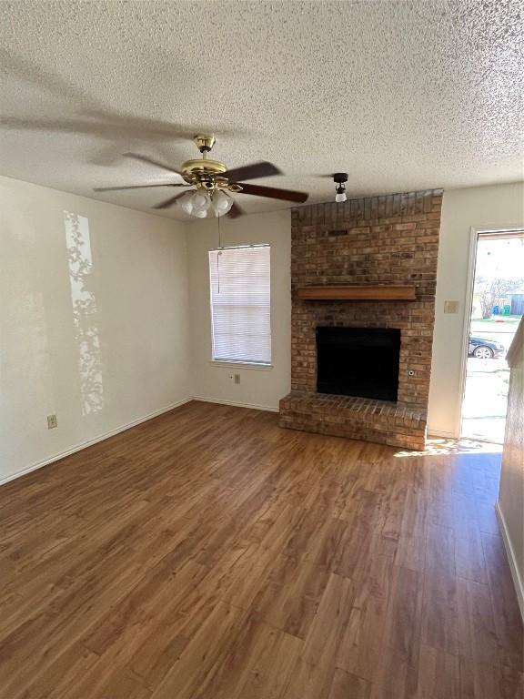 unfurnished living room featuring hardwood / wood-style flooring, ceiling fan, a fireplace, and a textured ceiling