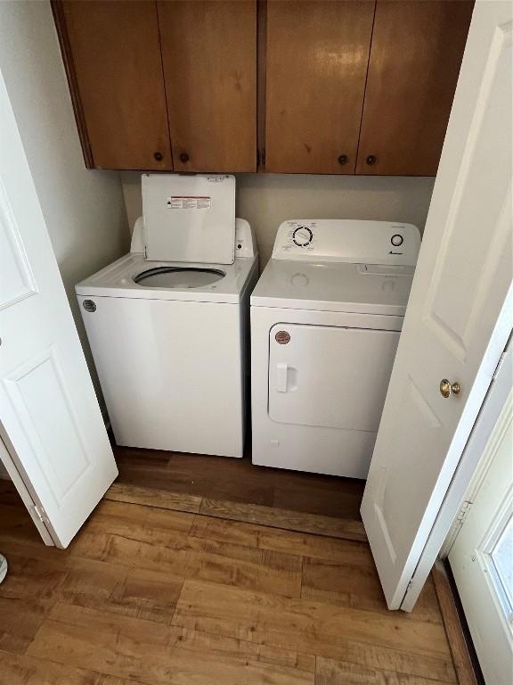 laundry room with washing machine and dryer, light hardwood / wood-style floors, and cabinets