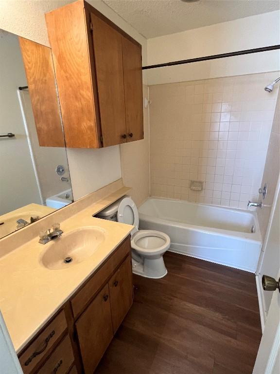 full bathroom featuring hardwood / wood-style floors, toilet, a textured ceiling, and tiled shower / bath