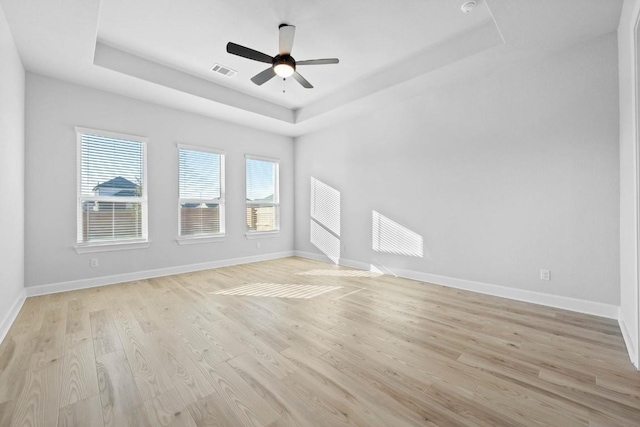 spare room featuring light hardwood / wood-style flooring, a raised ceiling, and ceiling fan