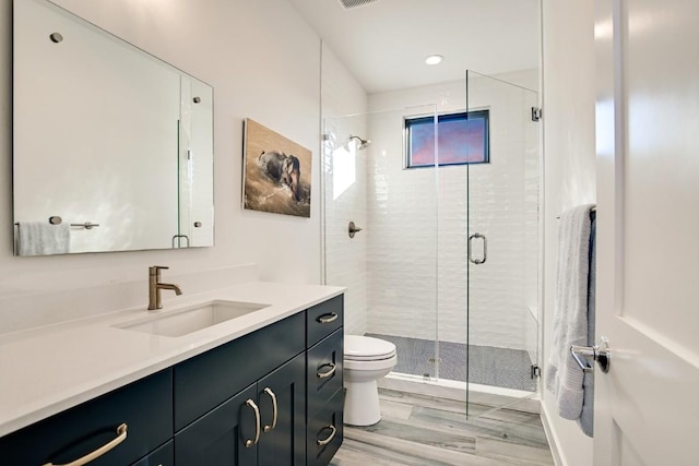 bathroom featuring hardwood / wood-style flooring, vanity, toilet, and an enclosed shower