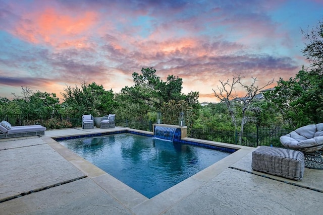 pool at dusk featuring a patio area and pool water feature