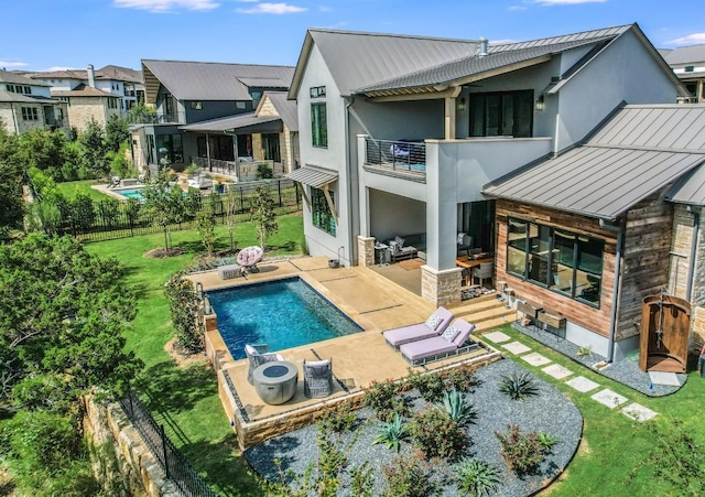 back of house with a patio area, a balcony, a fenced in pool, and a yard