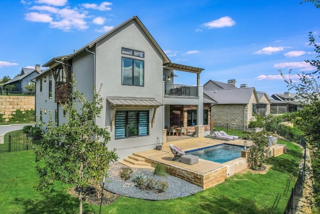 back of house featuring a balcony, a yard, and a fenced in pool