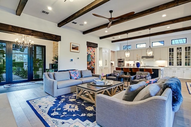 living room with beamed ceiling, plenty of natural light, ceiling fan with notable chandelier, and light hardwood / wood-style flooring