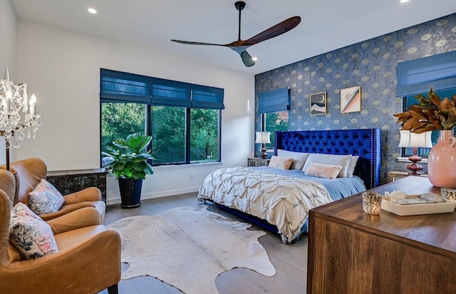 bedroom with light hardwood / wood-style floors and ceiling fan with notable chandelier