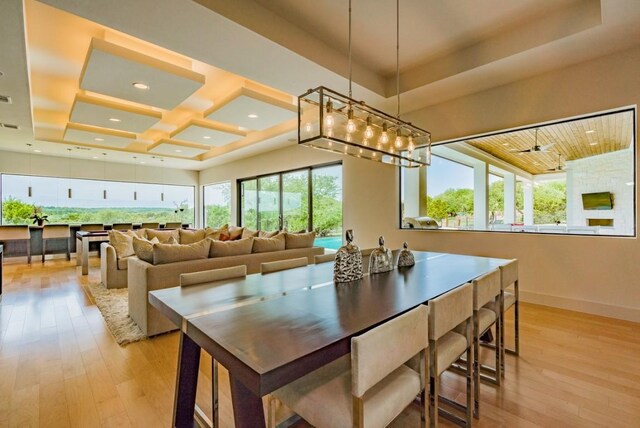 dining area with ceiling fan, light hardwood / wood-style floors, and a tray ceiling