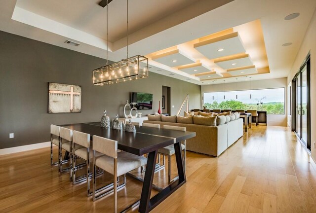 dining space featuring a tray ceiling and light hardwood / wood-style floors