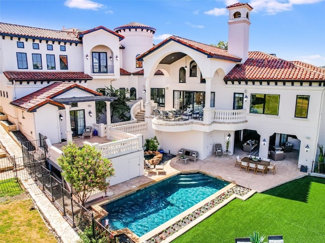 back of property with a fenced in pool, a yard, and a patio