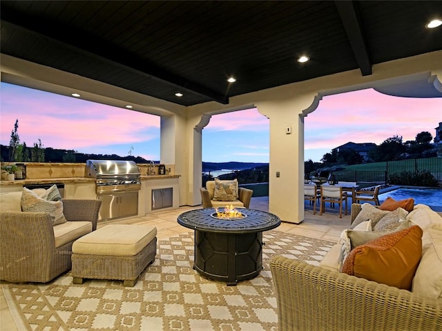 patio terrace at dusk with grilling area, area for grilling, and an outdoor living space with a fire pit