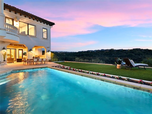 pool at dusk featuring an outdoor hangout area, a patio area, and a yard