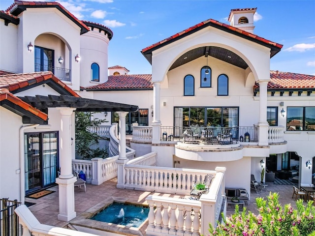 rear view of house with a pergola, a balcony, and a patio