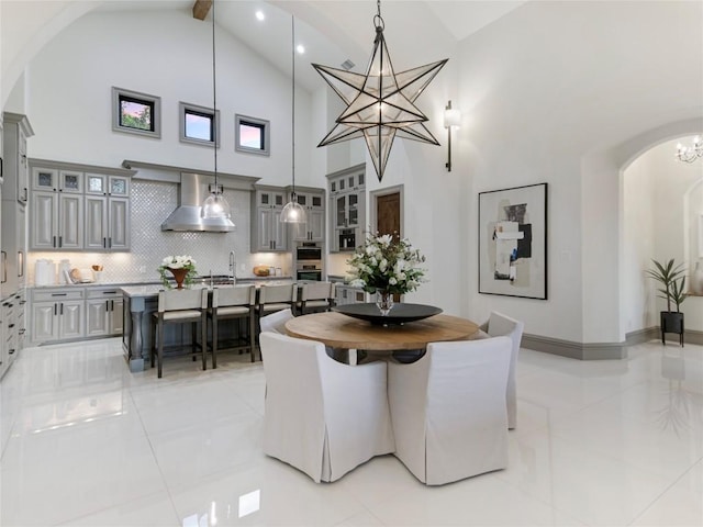 dining area with beam ceiling, high vaulted ceiling, light tile patterned floors, and an inviting chandelier