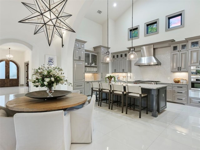 dining room featuring light tile patterned floors, a towering ceiling, an inviting chandelier, and french doors