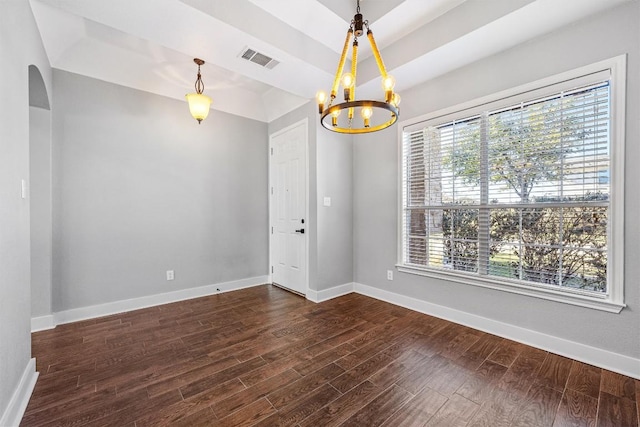 empty room featuring a raised ceiling, dark hardwood / wood-style flooring, and a chandelier