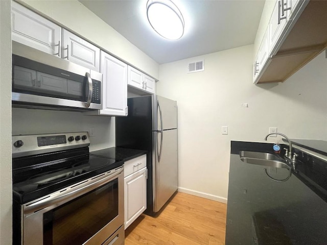 2207 Leon St Unit 309, Austin, TX 78705 - kitchen featuring appliances with stainless steel finishes, light wood-type flooring, and white cabinets