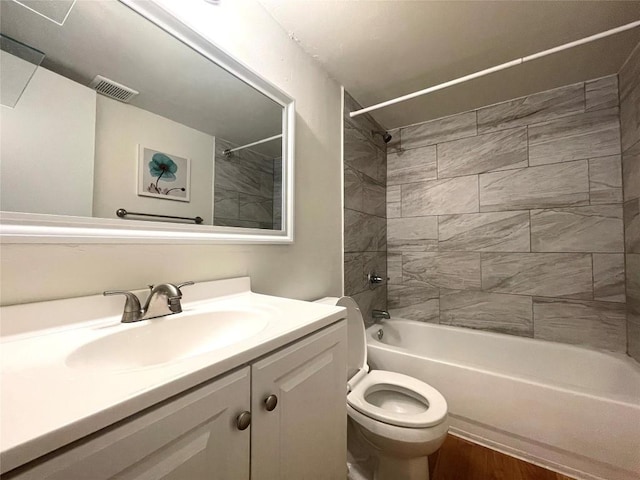 full bathroom with hardwood / wood-style floors, vanity, toilet, and tiled shower / bath