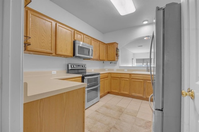 kitchen with light tile patterned floors, light brown cabinetry, sink, and appliances with stainless steel finishes