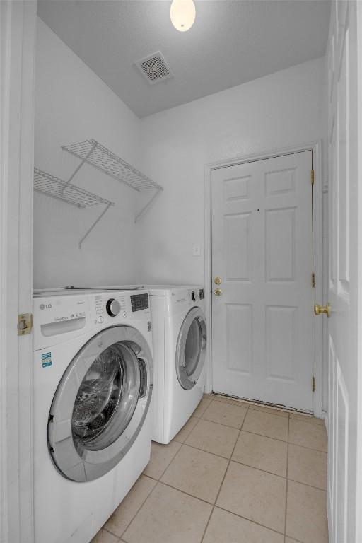 washroom featuring washer and clothes dryer and light tile patterned floors