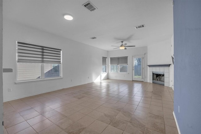 unfurnished living room featuring a tiled fireplace, ceiling fan, and light tile patterned floors