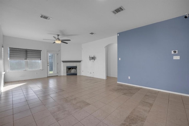 unfurnished living room with a tiled fireplace, ceiling fan, and light tile patterned floors