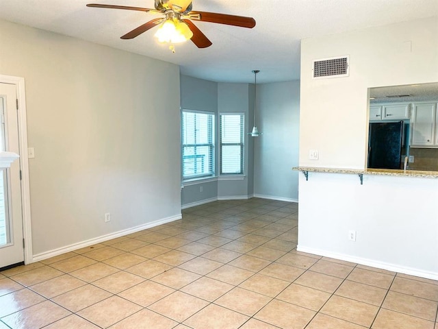 tiled spare room featuring ceiling fan