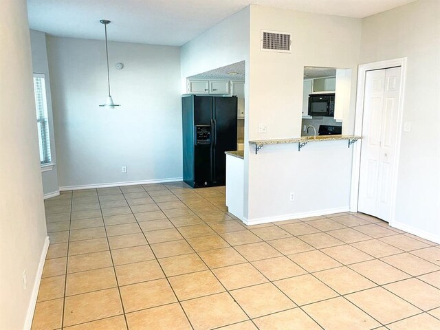 kitchen featuring black appliances, pendant lighting, kitchen peninsula, and light tile patterned floors