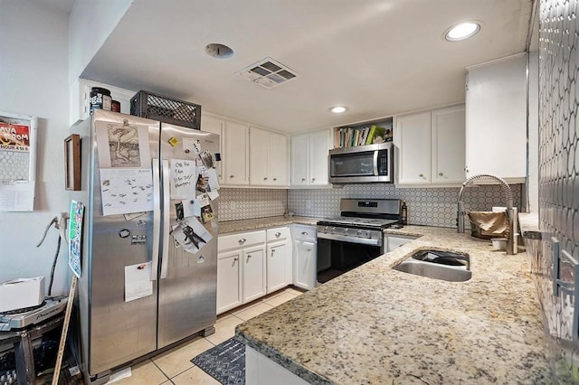 kitchen featuring light stone countertops, sink, light tile patterned flooring, white cabinets, and appliances with stainless steel finishes