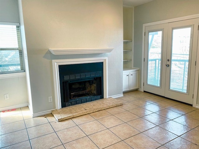 unfurnished living room featuring built in shelves, french doors, and light tile patterned flooring