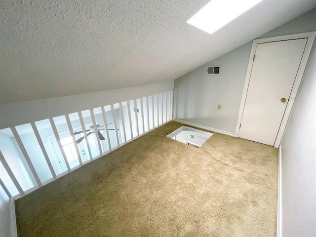 bonus room featuring a textured ceiling, light colored carpet, and lofted ceiling with skylight