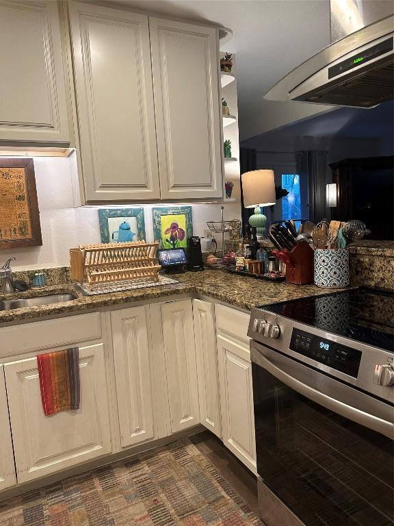 kitchen with open shelves, electric range, white cabinetry, dark stone countertops, and wall chimney exhaust hood