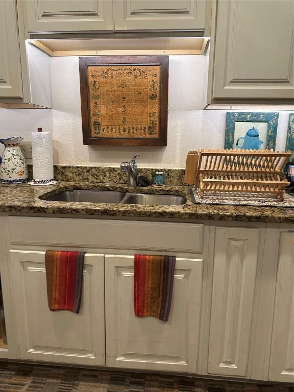 interior space with dark stone counters, white cabinetry, and a sink