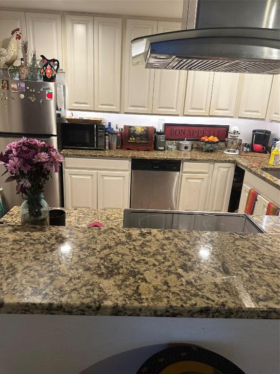 kitchen featuring stainless steel appliances, dark stone counters, white cabinetry, and island range hood