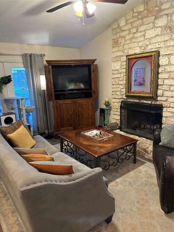 living area featuring lofted ceiling, a fireplace, and a ceiling fan