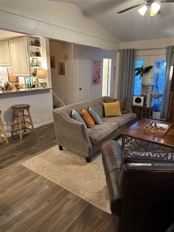 living area with dark wood-style floors, vaulted ceiling, and a ceiling fan