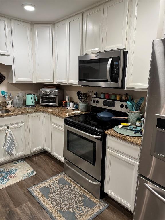 kitchen featuring stainless steel appliances, dark stone countertops, and white cabinets