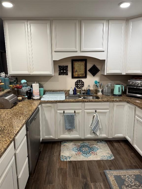 kitchen featuring stone countertops, white cabinetry, dark wood-style flooring, and stainless steel dishwasher