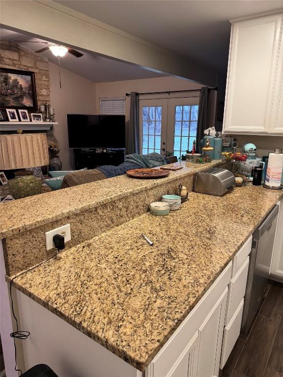 kitchen featuring light stone counters, white cabinets, a peninsula, and stainless steel dishwasher