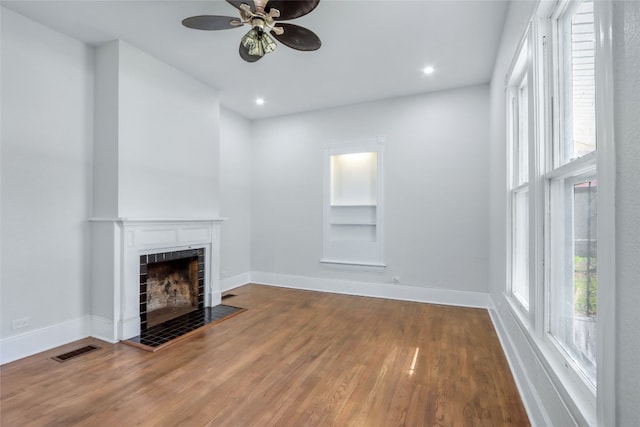 unfurnished living room featuring ceiling fan, a fireplace, and hardwood / wood-style floors