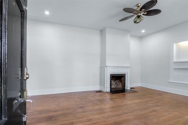 unfurnished living room with ceiling fan, dark hardwood / wood-style floors, and a brick fireplace