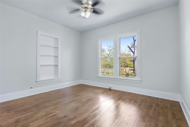 spare room with ceiling fan, dark hardwood / wood-style flooring, and built in features