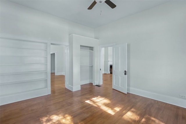 unfurnished room with wood-type flooring, built in features, and ceiling fan