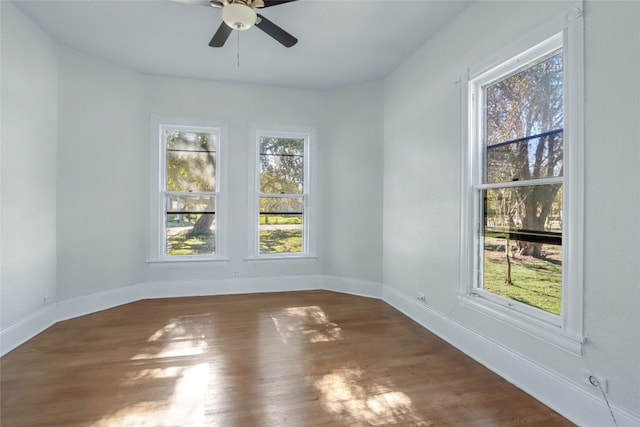 unfurnished room with dark hardwood / wood-style floors, a healthy amount of sunlight, and ceiling fan