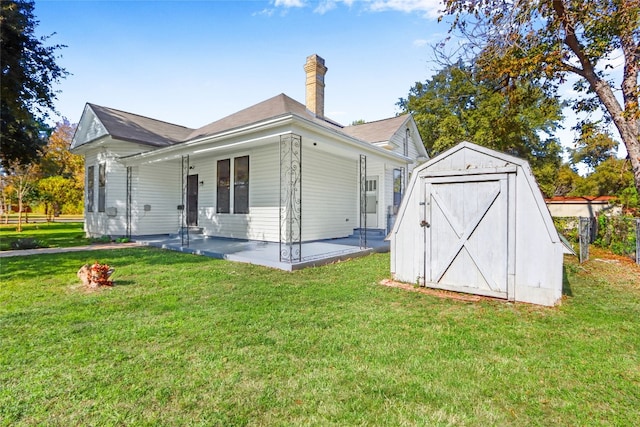 rear view of property featuring a lawn, a storage shed, and a patio